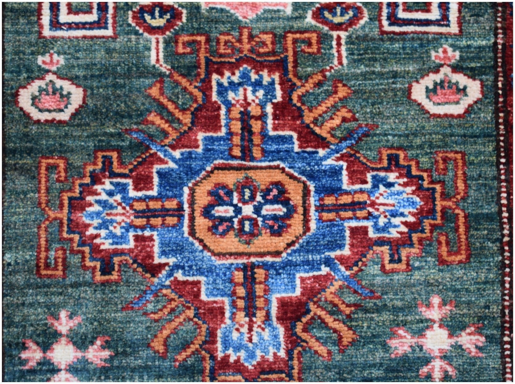 An Afghan Super Kazakh runner featuring a central geometric medallion in blue, red, and orange.