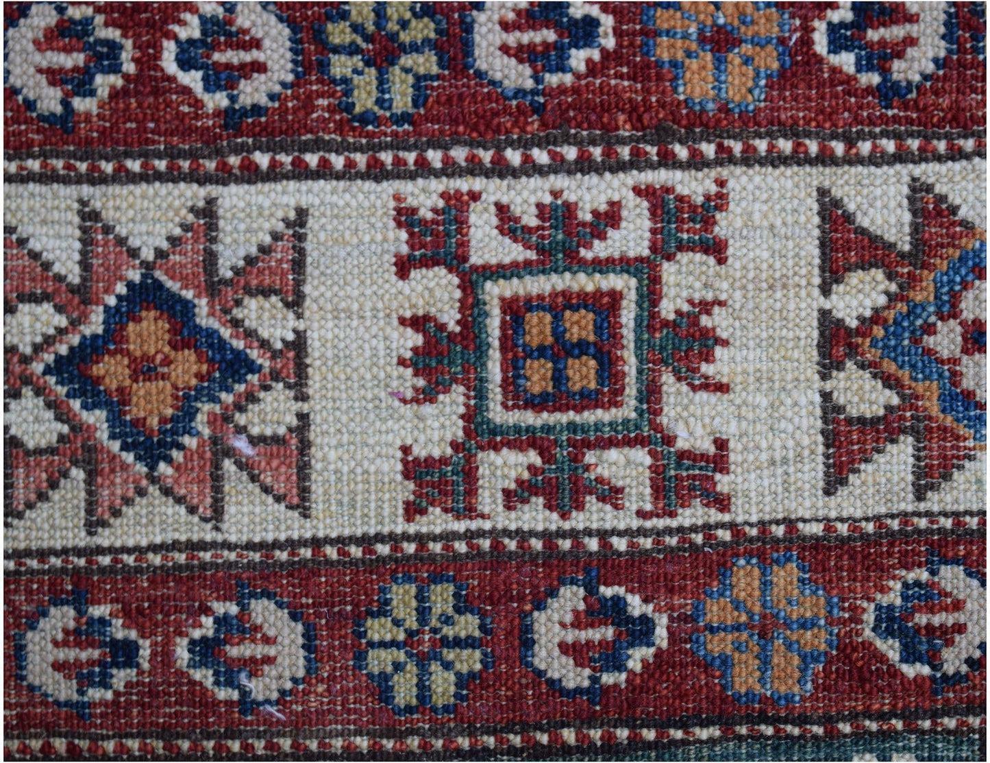 A close-up of an Afghan Super Kazakh runner featuring traditional geometric motifs in wool.