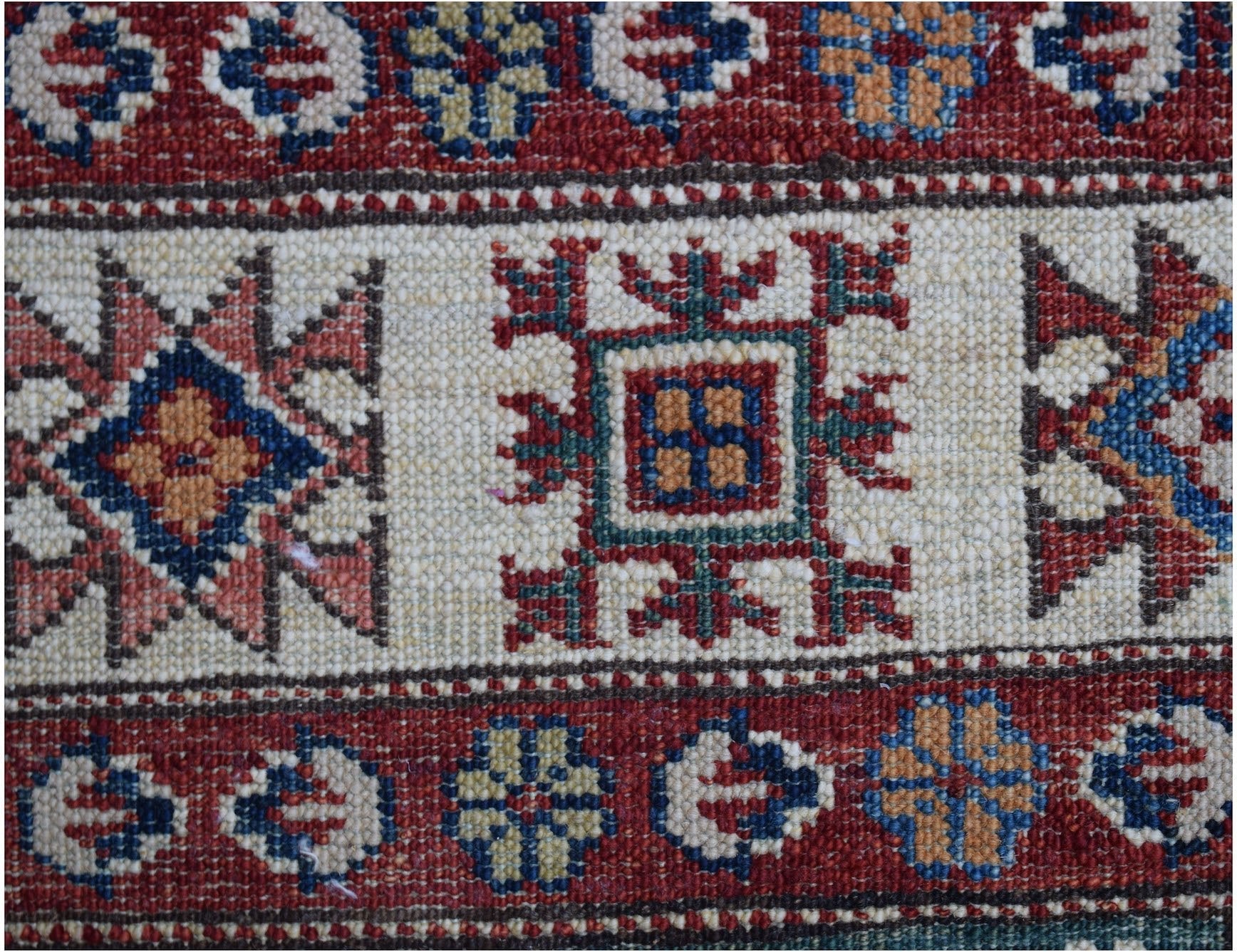 A close-up of an Afghan Super Kazakh runner featuring traditional geometric motifs in wool.