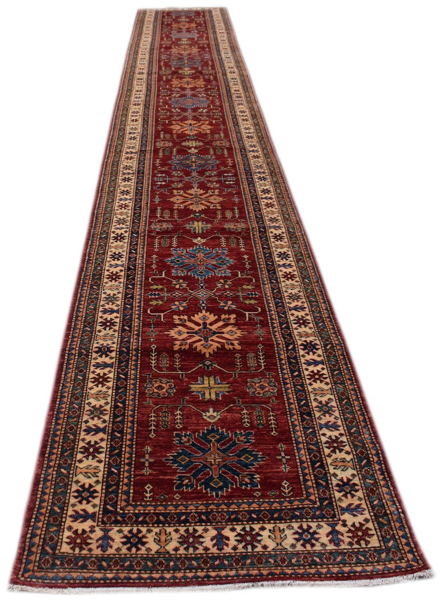 A long, handmade Afghan Super Kazakh runner rug featuring traditional geometric motifs in red.