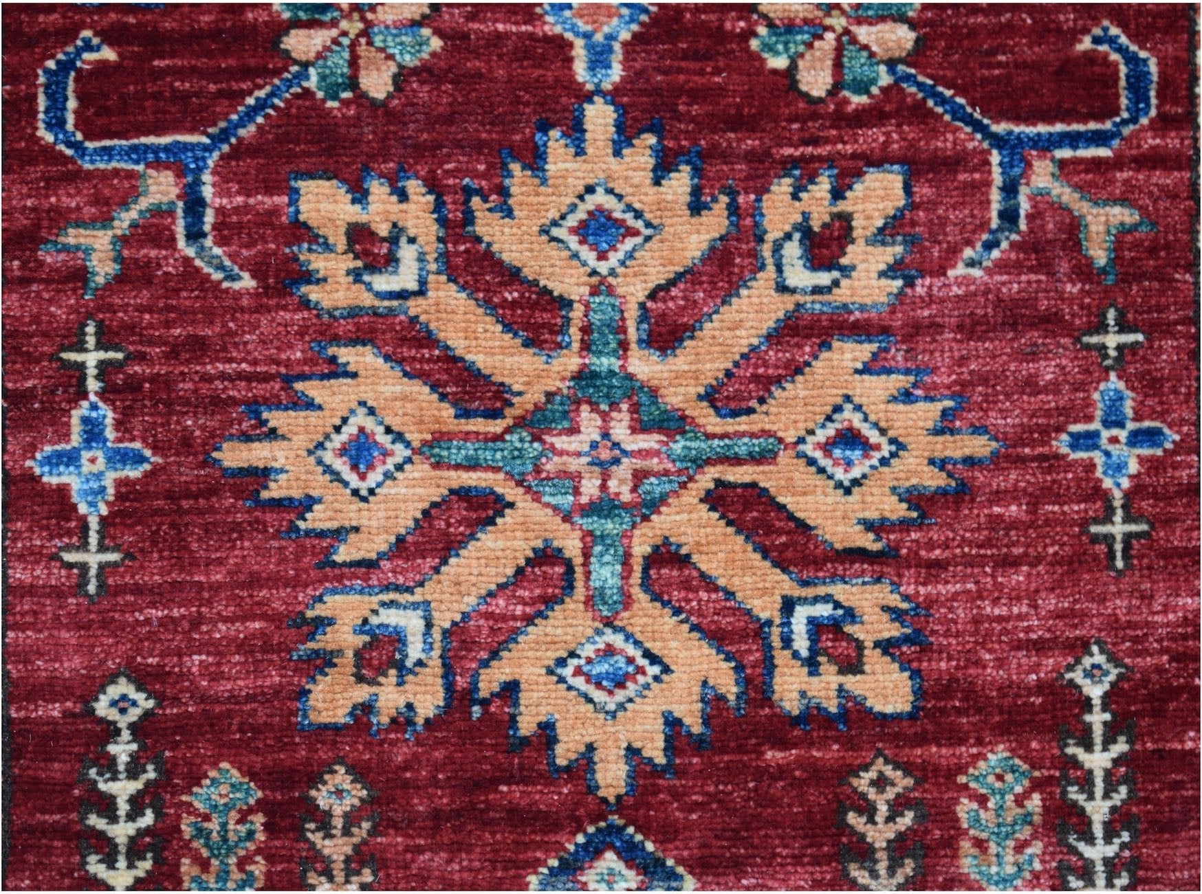 A handmade Afghan Super Kazakh runner featuring a central geometric floral motif on a red field.