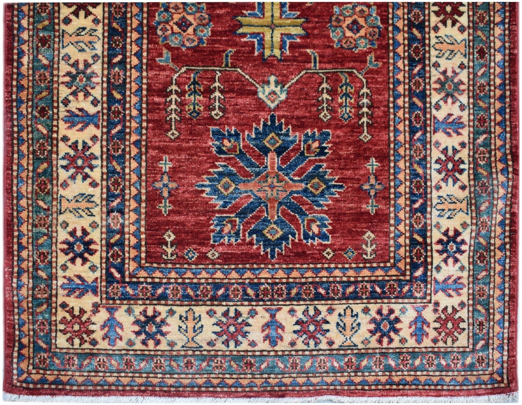 An Afghan Super Kazakh runner featuring a red field with a central blue geometric medallion.