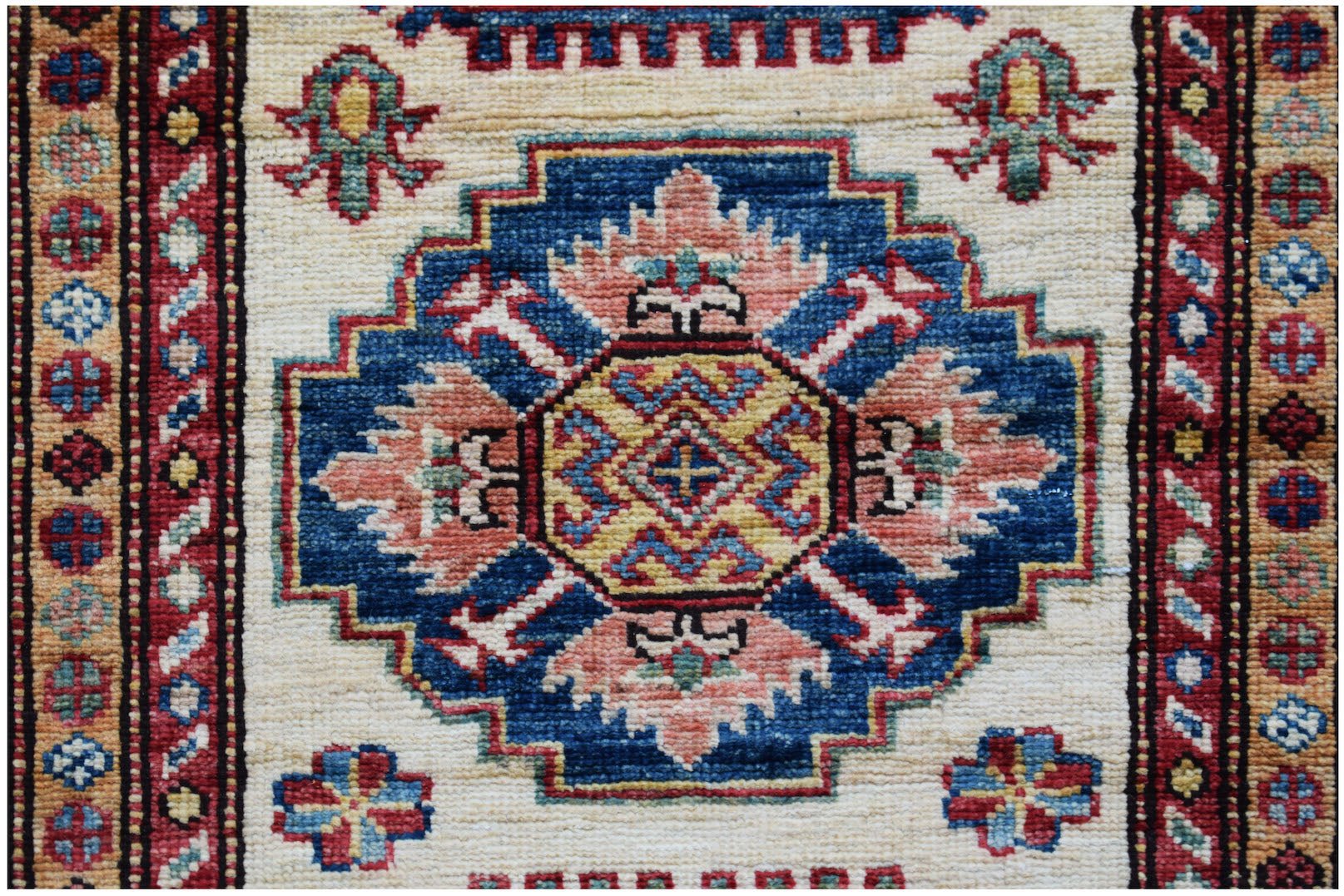 An Afghan Super Kazakh runner featuring a central geometric medallion in blue, pink, and yellow.