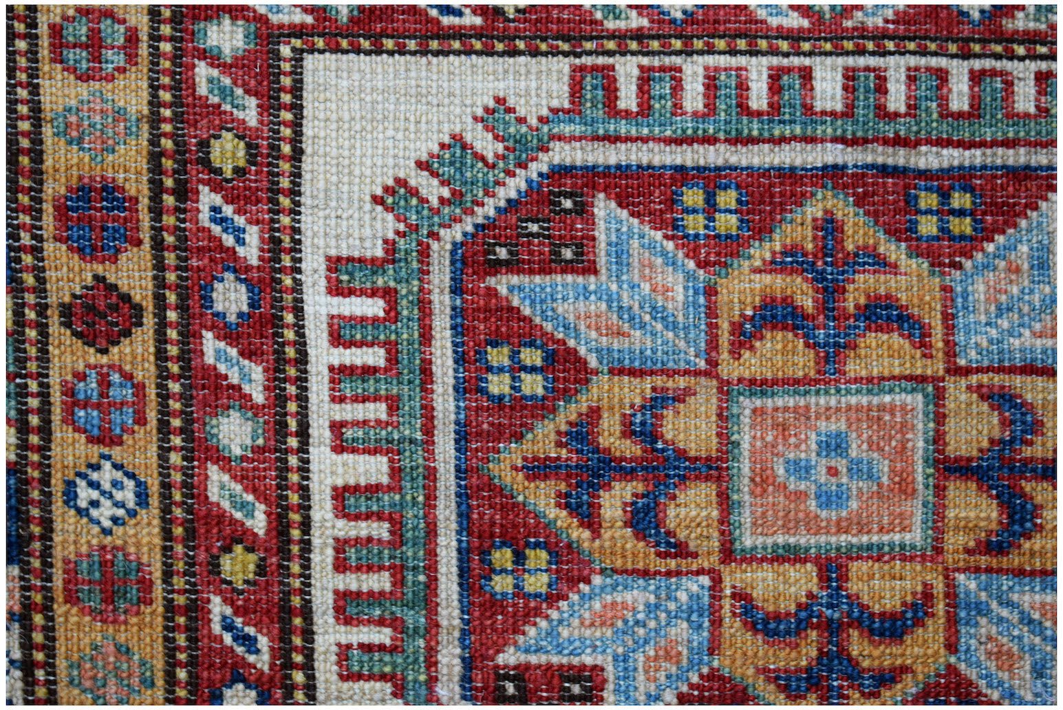 A close-up of an Afghan Super Kazakh runner featuring traditional geometric motifs in vibrant colors.