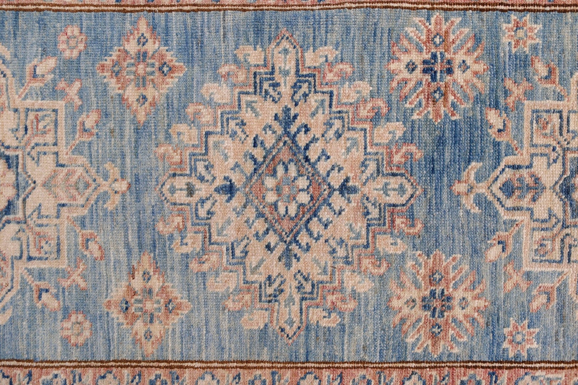 An Afghan Super Kazakh runner featuring traditional geometric motifs in blue, cream, and pink.
