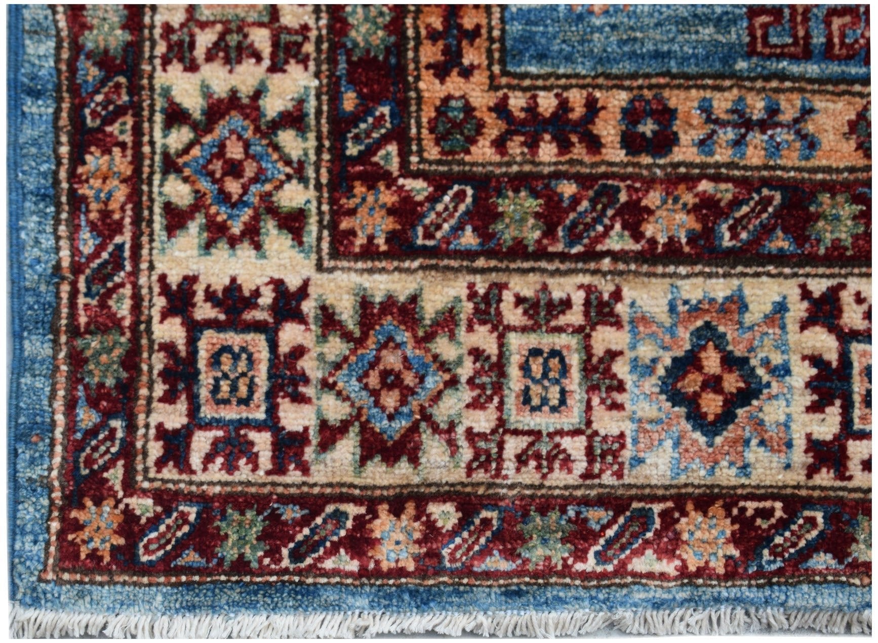 A close-up of an Afghan Super Kazakh runner featuring traditional geometric motifs in blue and red.