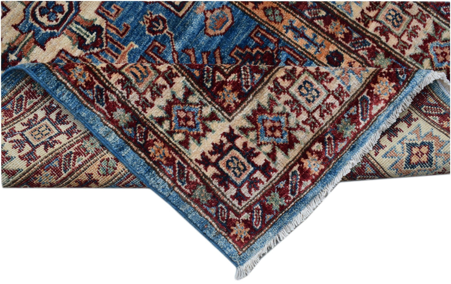 A folded Afghan Super Kazakh runner featuring traditional geometric motifs in blue and red wool.