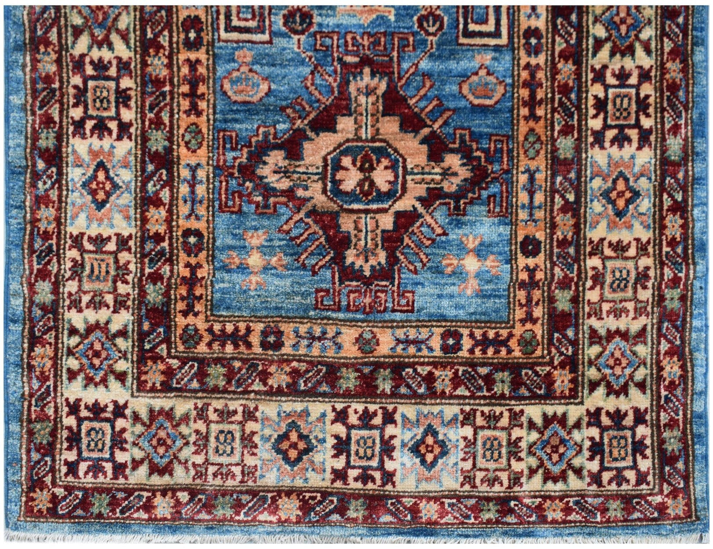 An Afghan Super Kazakh runner rug featuring a blue field with a central geometric medallion.