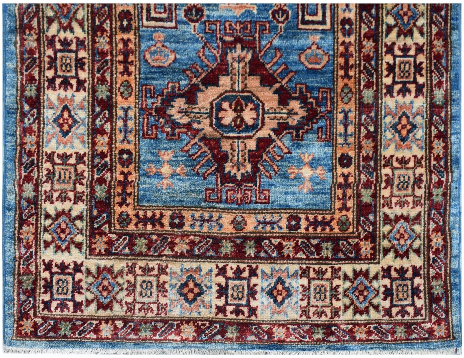 An Afghan Super Kazakh runner rug featuring a blue field with a central geometric medallion.