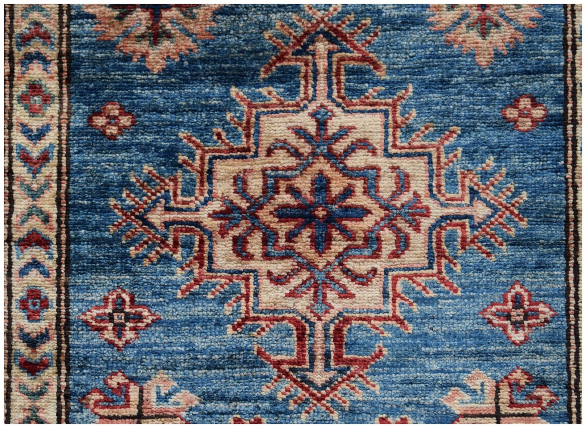 Handmade Afghan Super Kazakh runner featuring a central geometric medallion on a blue field.