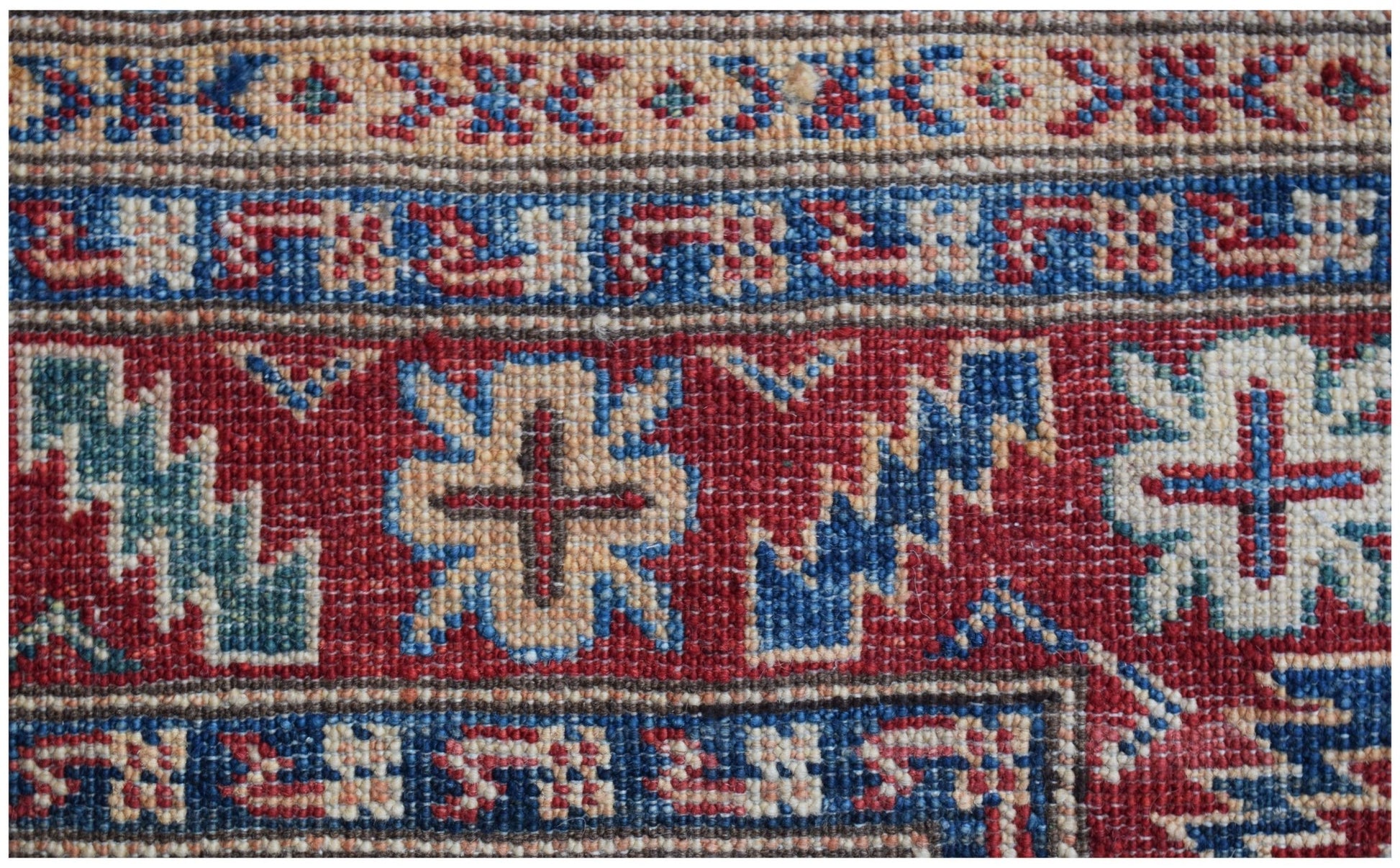 A close-up of an Afghan Super Kazakh runner featuring traditional geometric motifs in red and blue.