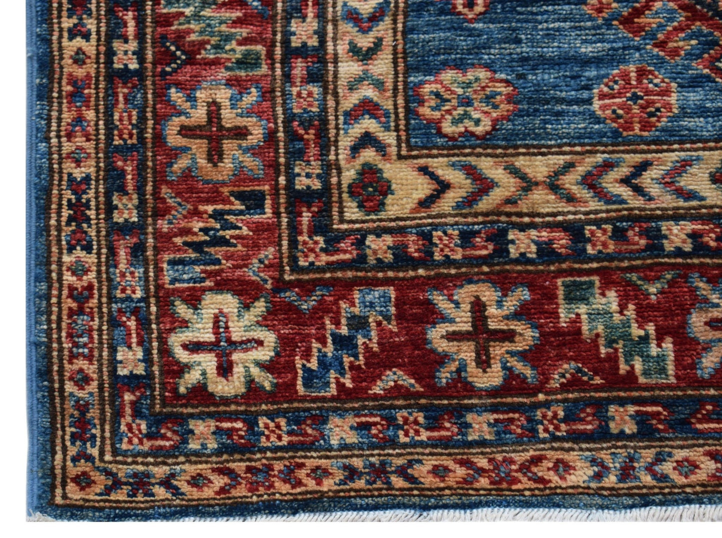 A corner view of a handmade Afghan Super Kazakh runner featuring traditional geometric motifs.