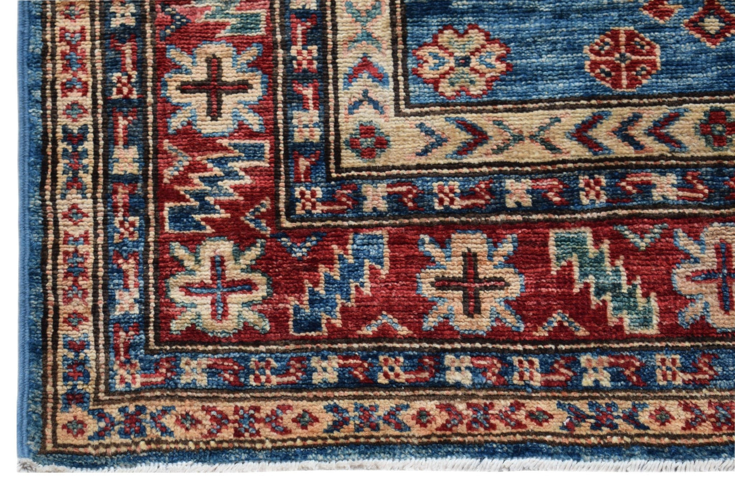A corner view of a handmade Afghan Super Kazakh runner featuring traditional geometric motifs.
