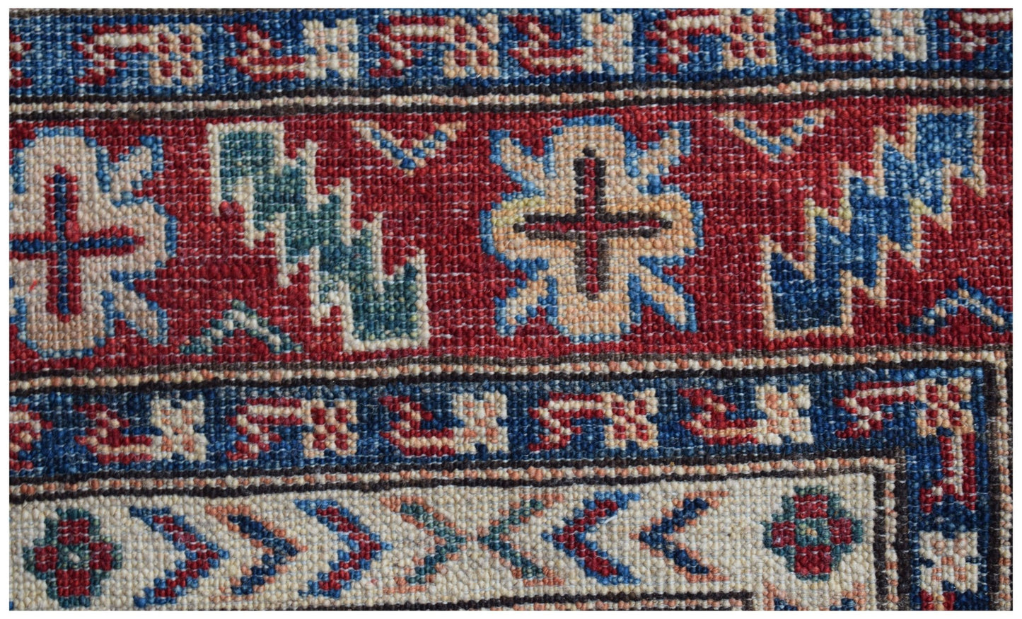 A close-up of an Afghan Super Kazakh runner featuring traditional geometric motifs in red and blue.