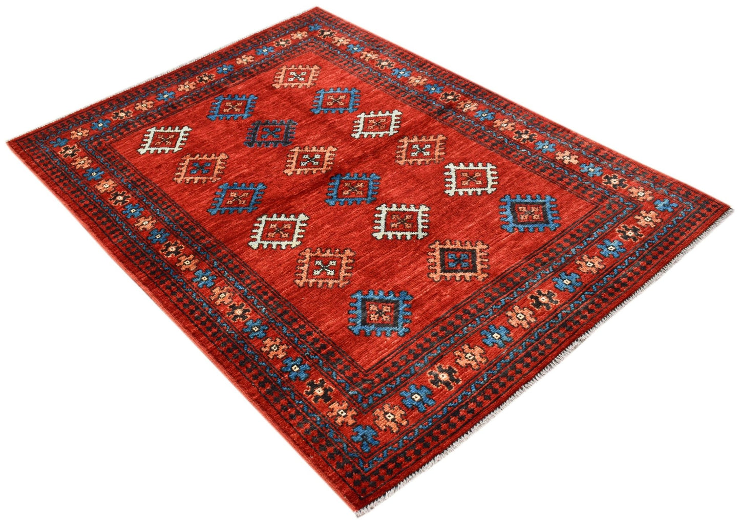A handwoven Afghan Pashm rug featuring a red field with repeating geometric motifs.