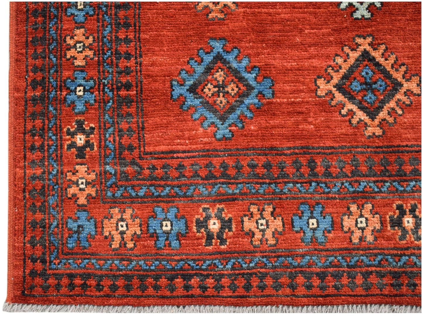 A handwoven Afghan Pashm rug featuring traditional geometric patterns in red, blue, and black.