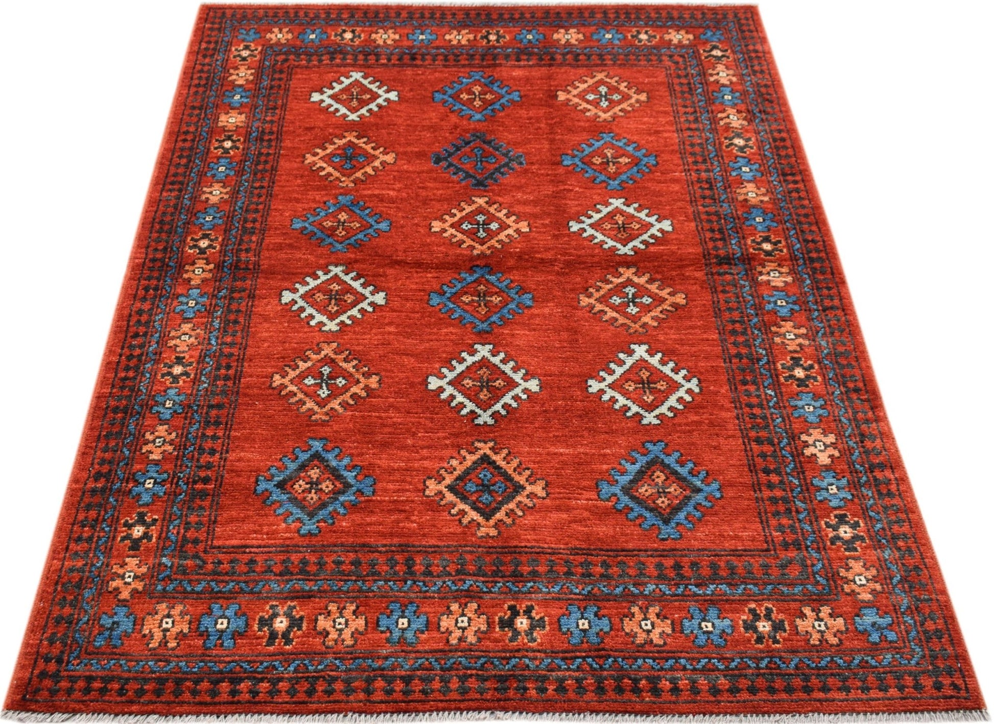 A handwoven Afghan Pashm rug featuring a red field with repeating geometric motifs.