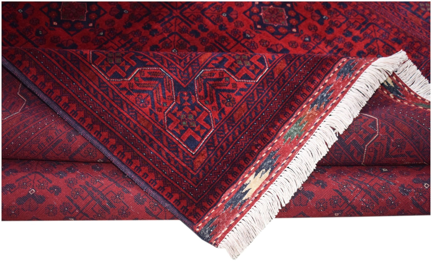 A handmade Afghan Biljik rug featuring deep red and blue geometric patterns with white fringe.