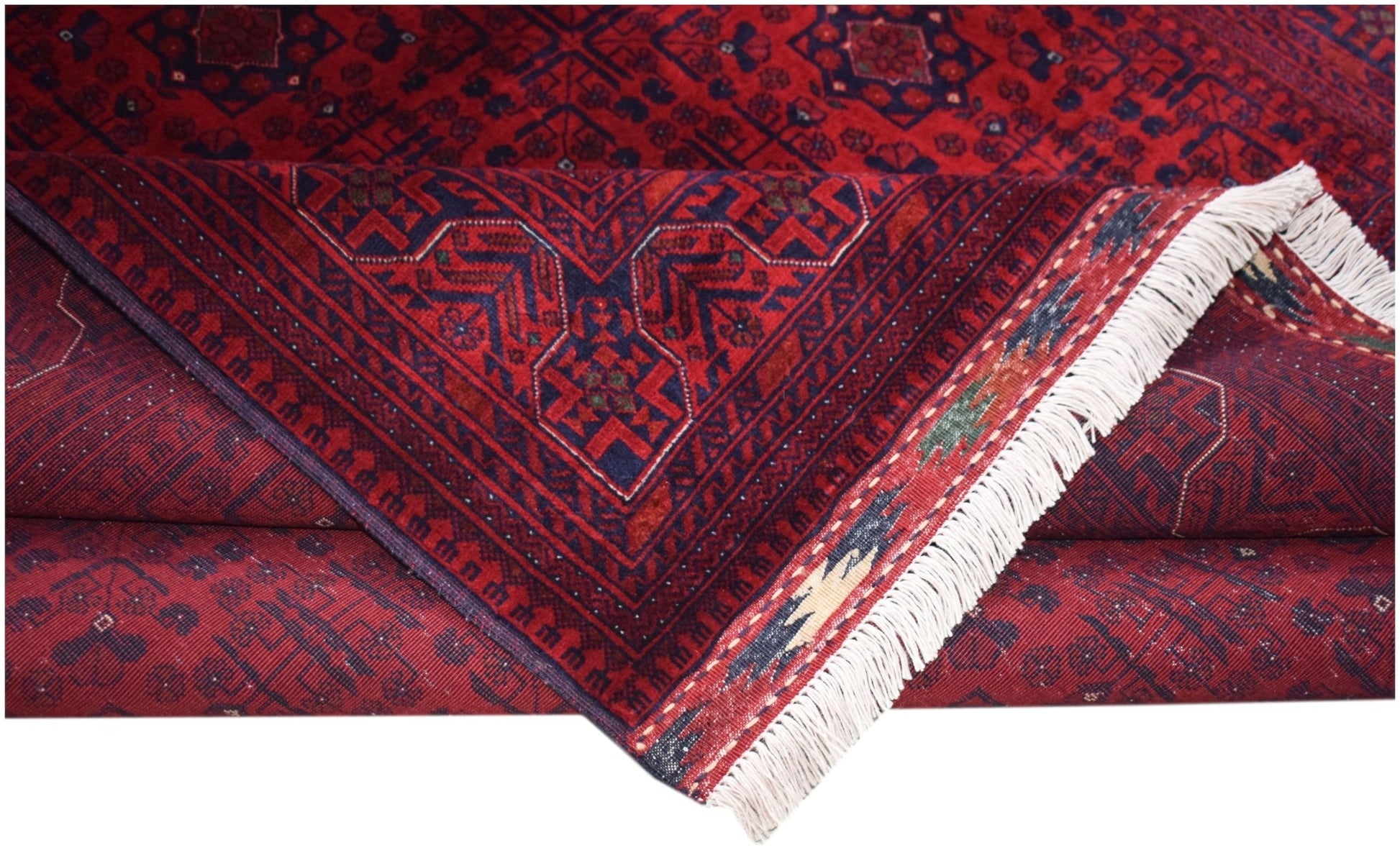 A handmade Afghan Biljik rug featuring deep red and blue geometric patterns with white fringe.