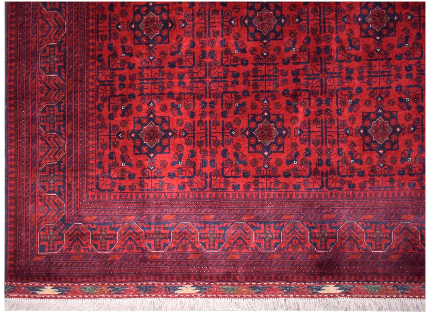 An Afghan Biljik rug featuring a deep red field with intricate blue geometric floral patterns.