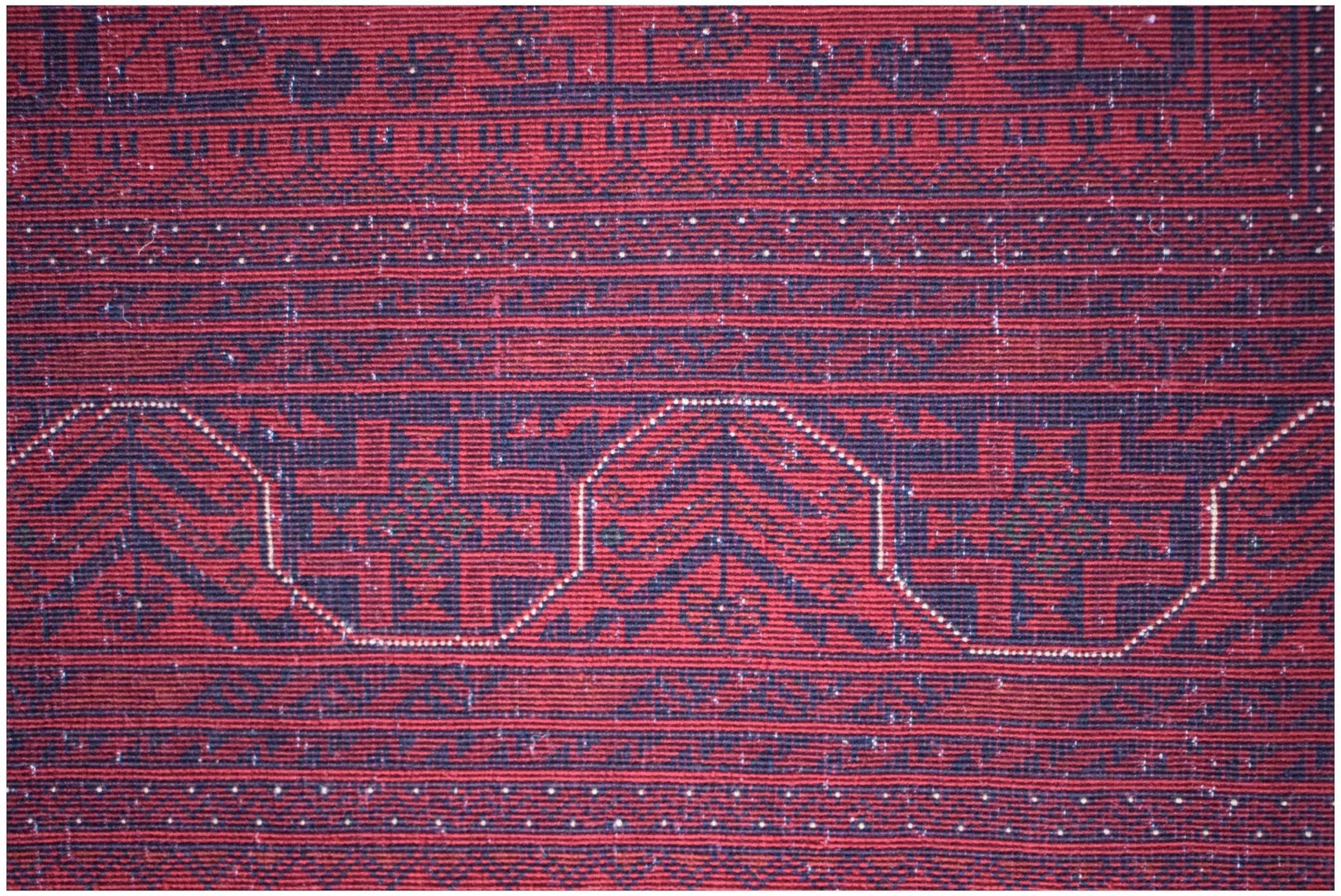 A close-up of an Afghan Biljik rug featuring intricate geometric patterns in deep red and blue.