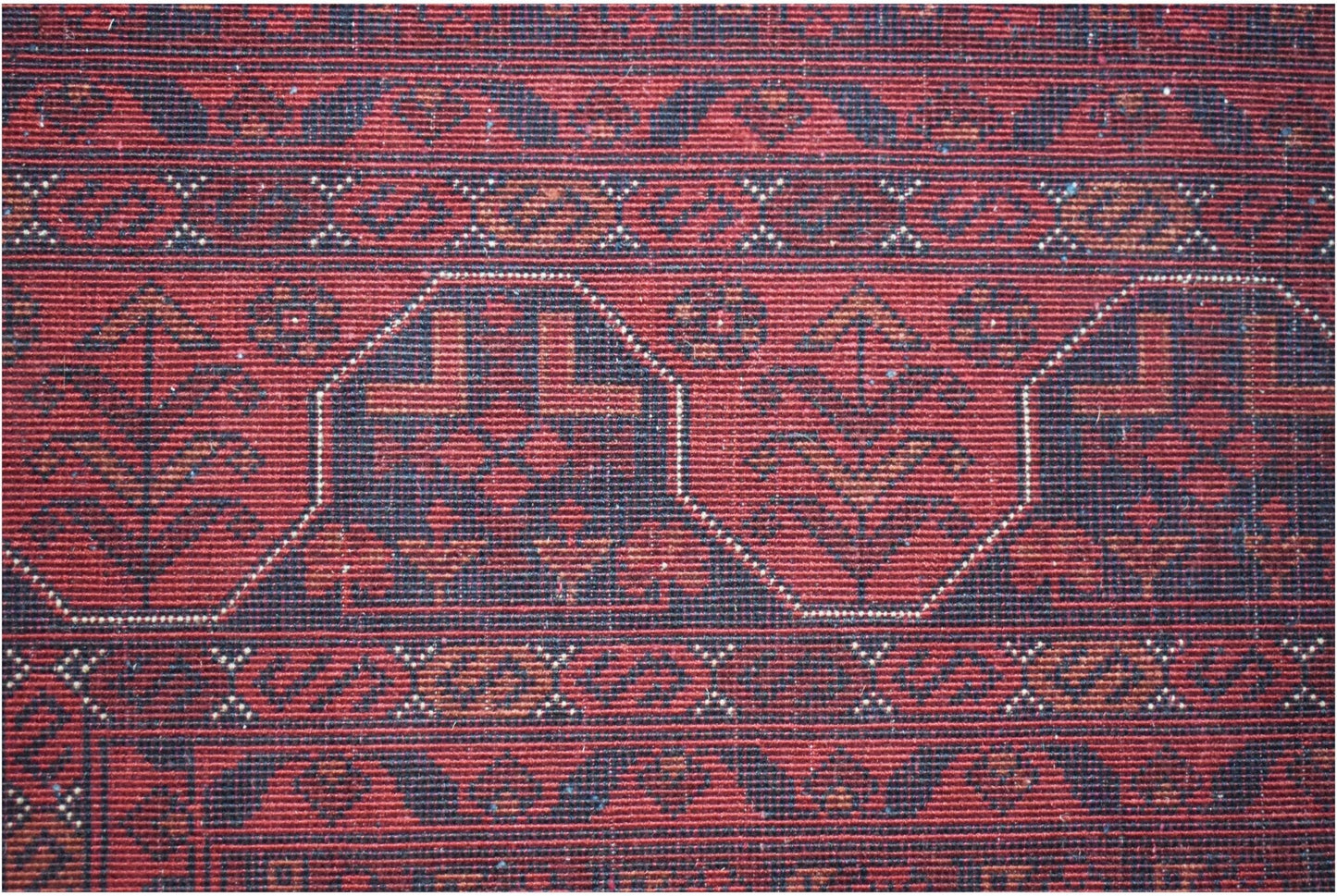 A handmade Afghan Biljik rug featuring deep red and blue tones with intricate geometric patterns.