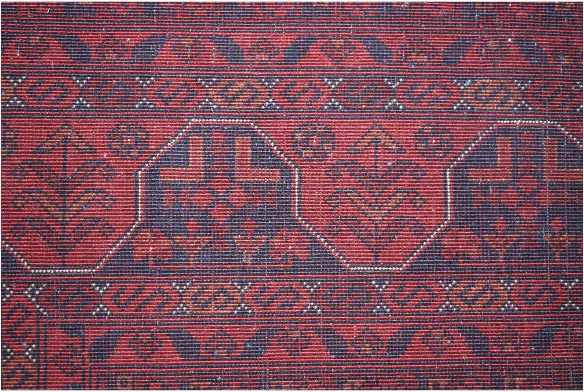 A handmade Afghan Biljik rug featuring deep red and blue tones with intricate geometric patterns.