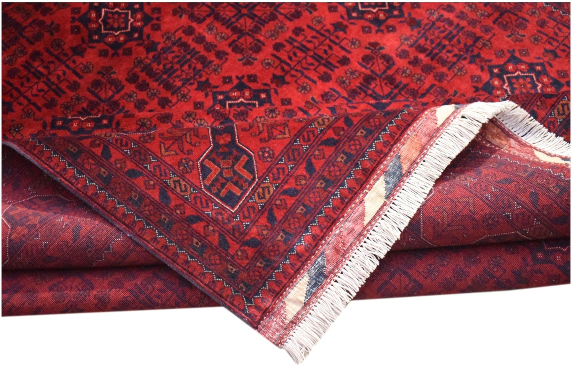 A handmade Afghan Biljik rug featuring deep red and blue geometric patterns with white fringe.