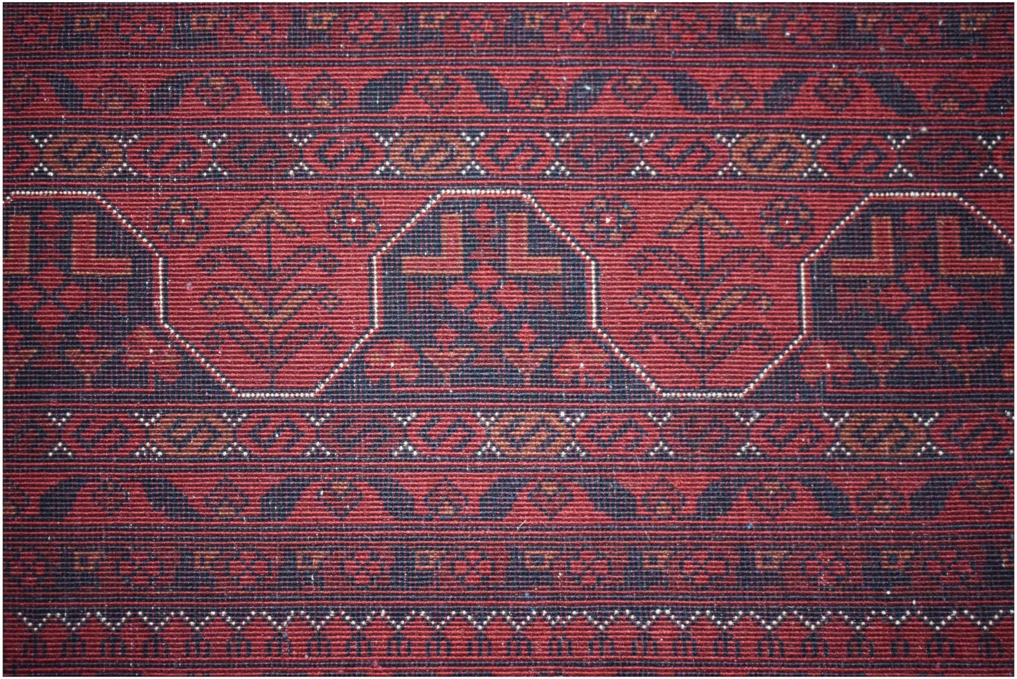 A handmade Afghan Biljik rug featuring intricate geometric patterns in deep red and blue wool.