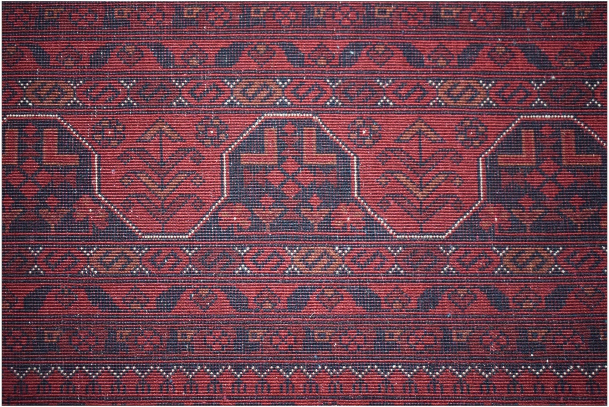 A handmade Afghan Biljik rug featuring intricate geometric patterns in deep red and blue wool.