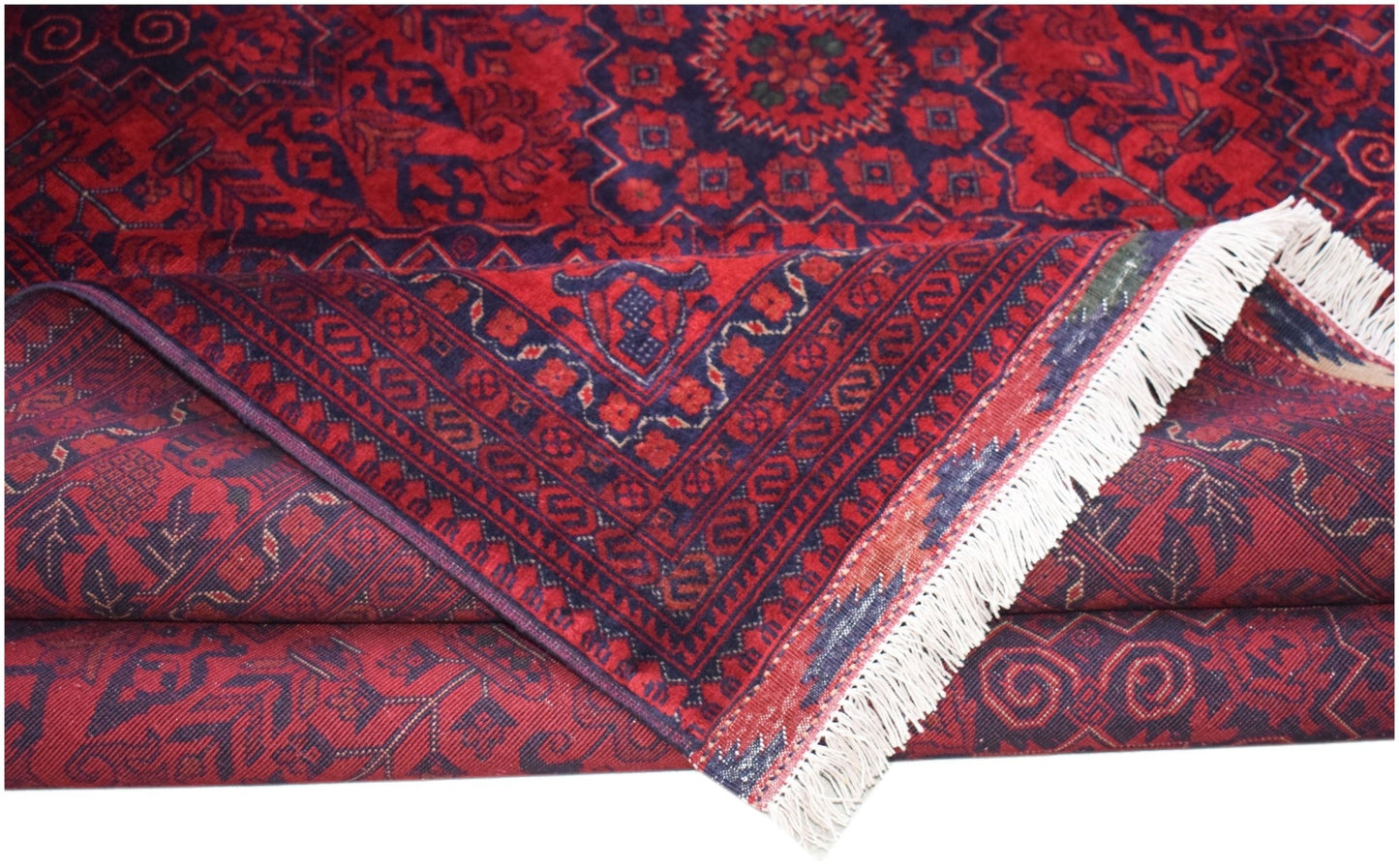 A handmade Afghan Biljik rug featuring deep red and blue geometric patterns with white fringe.