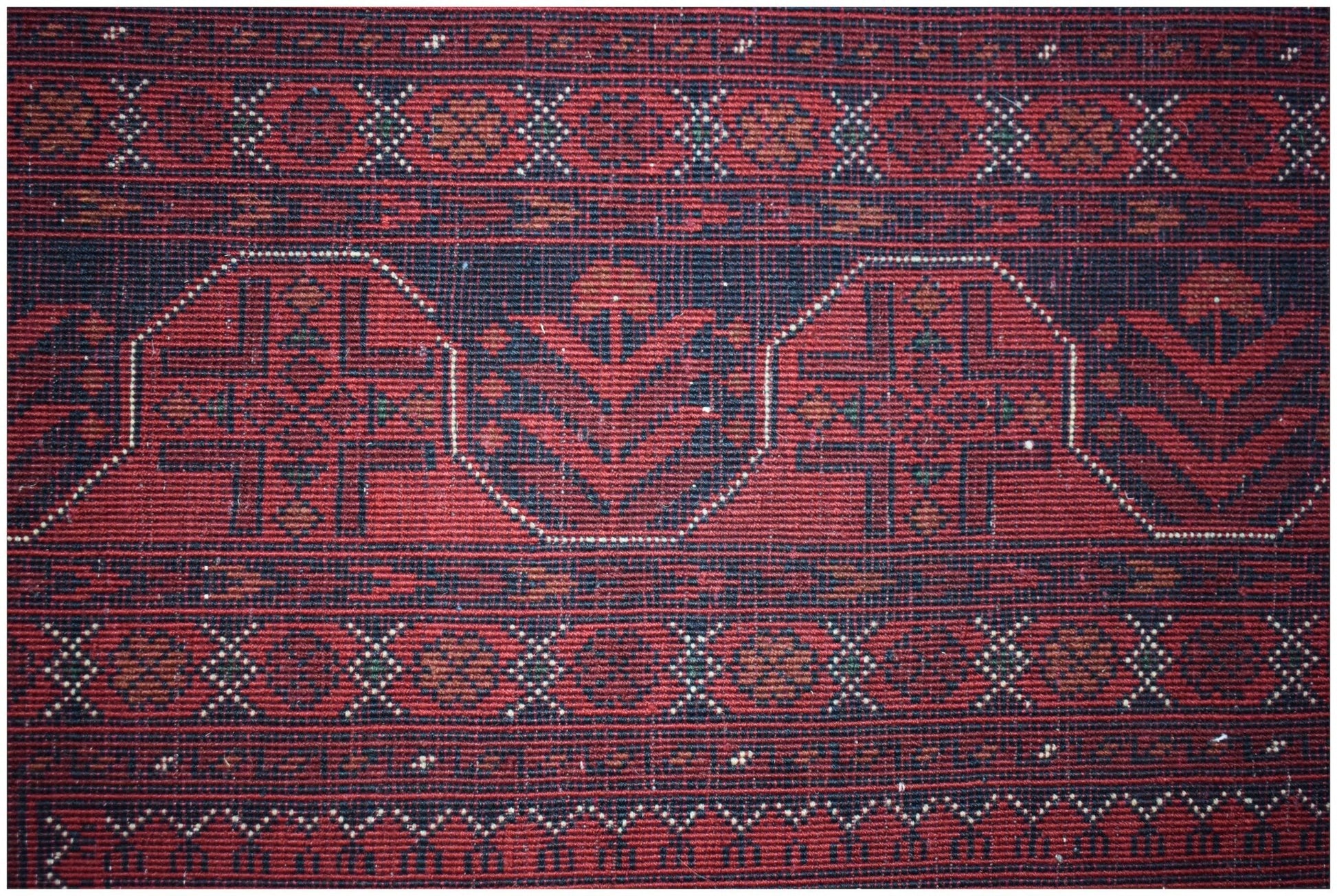A handmade Afghan Biljik rug featuring intricate geometric patterns in deep red and blue wool.