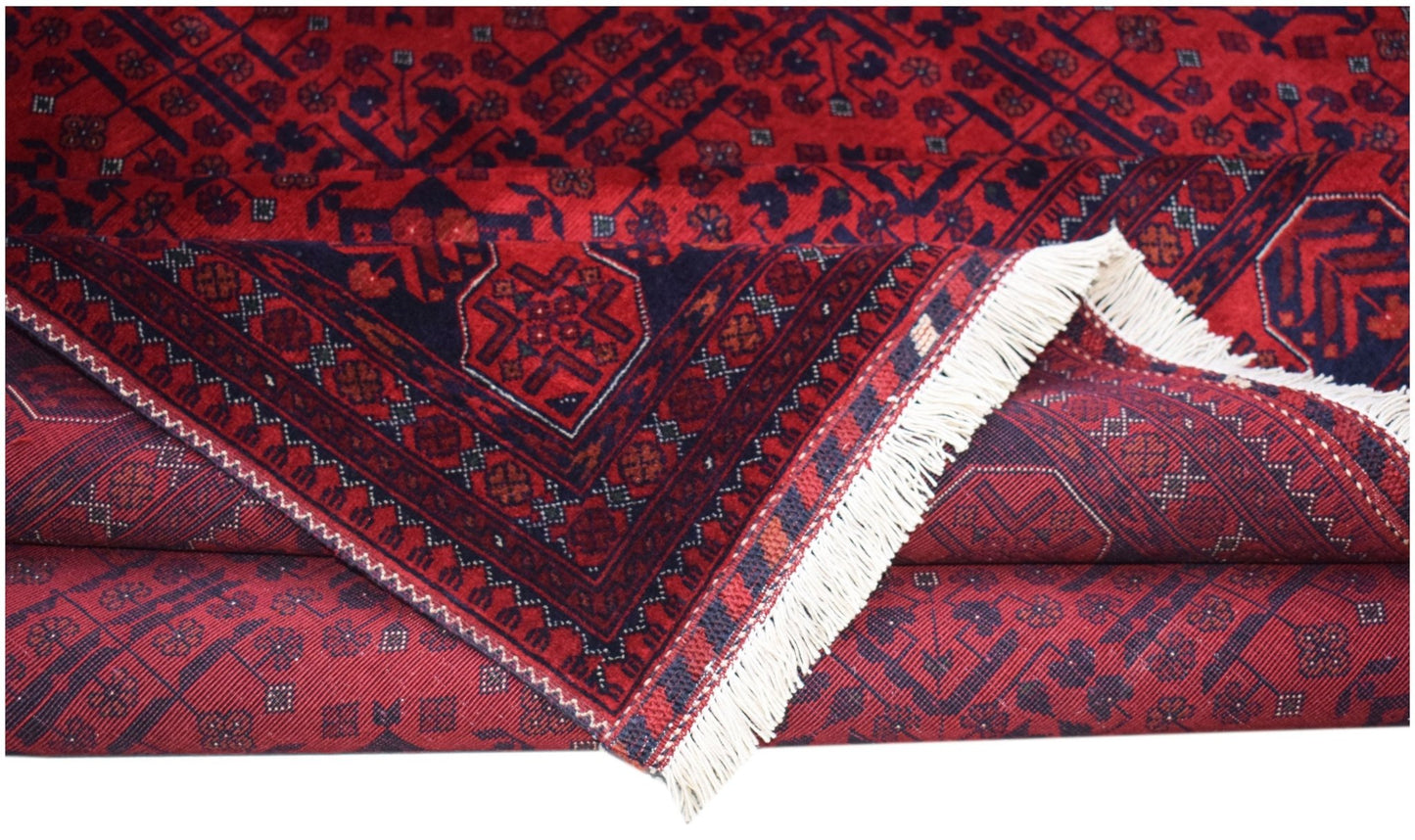 A handmade Afghan Biljik rug featuring deep red and blue geometric patterns with white fringe.