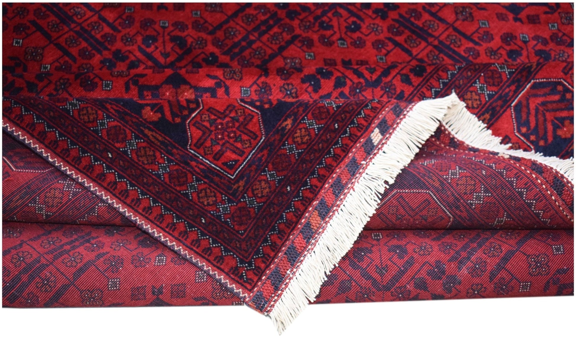 A handmade Afghan Biljik rug featuring deep red and blue geometric patterns with white fringe.