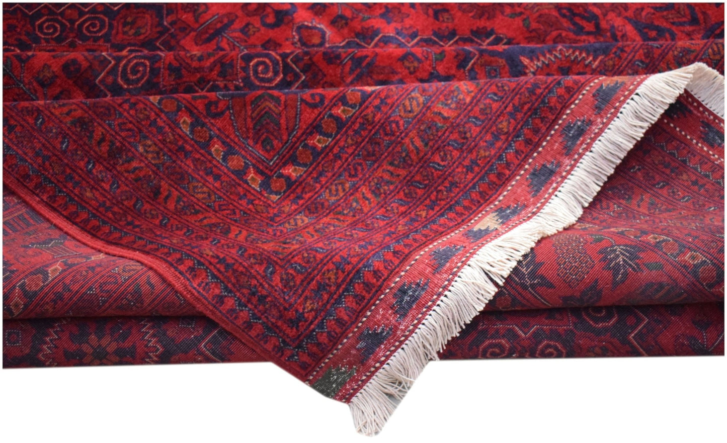 A folded Afghan Biljik rug featuring intricate geometric patterns in deep red and blue wool.