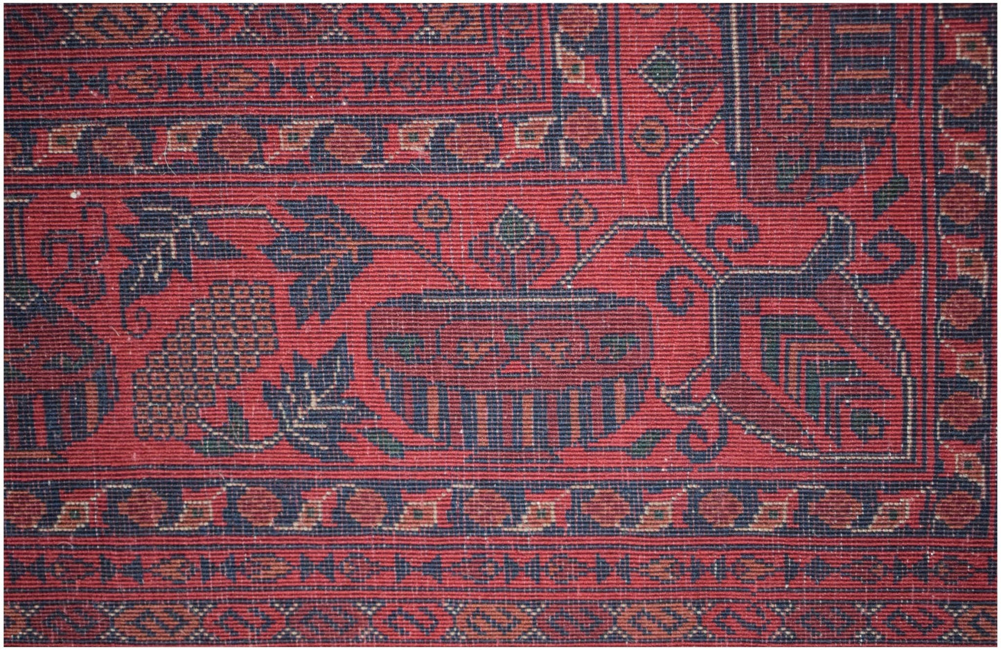 A close-up of a handmade Afghan Biljik rug featuring intricate floral and geometric patterns in red.
