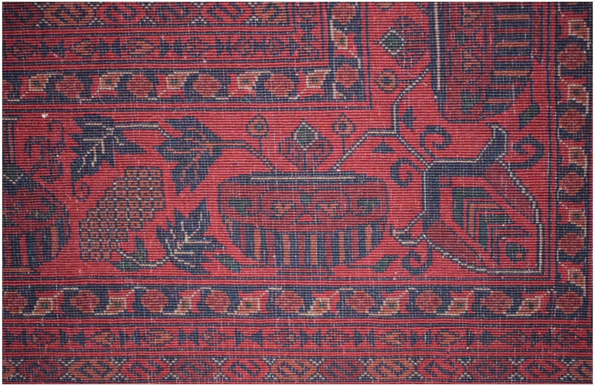 A close-up of a handmade Afghan Biljik rug featuring intricate floral and geometric patterns in red.