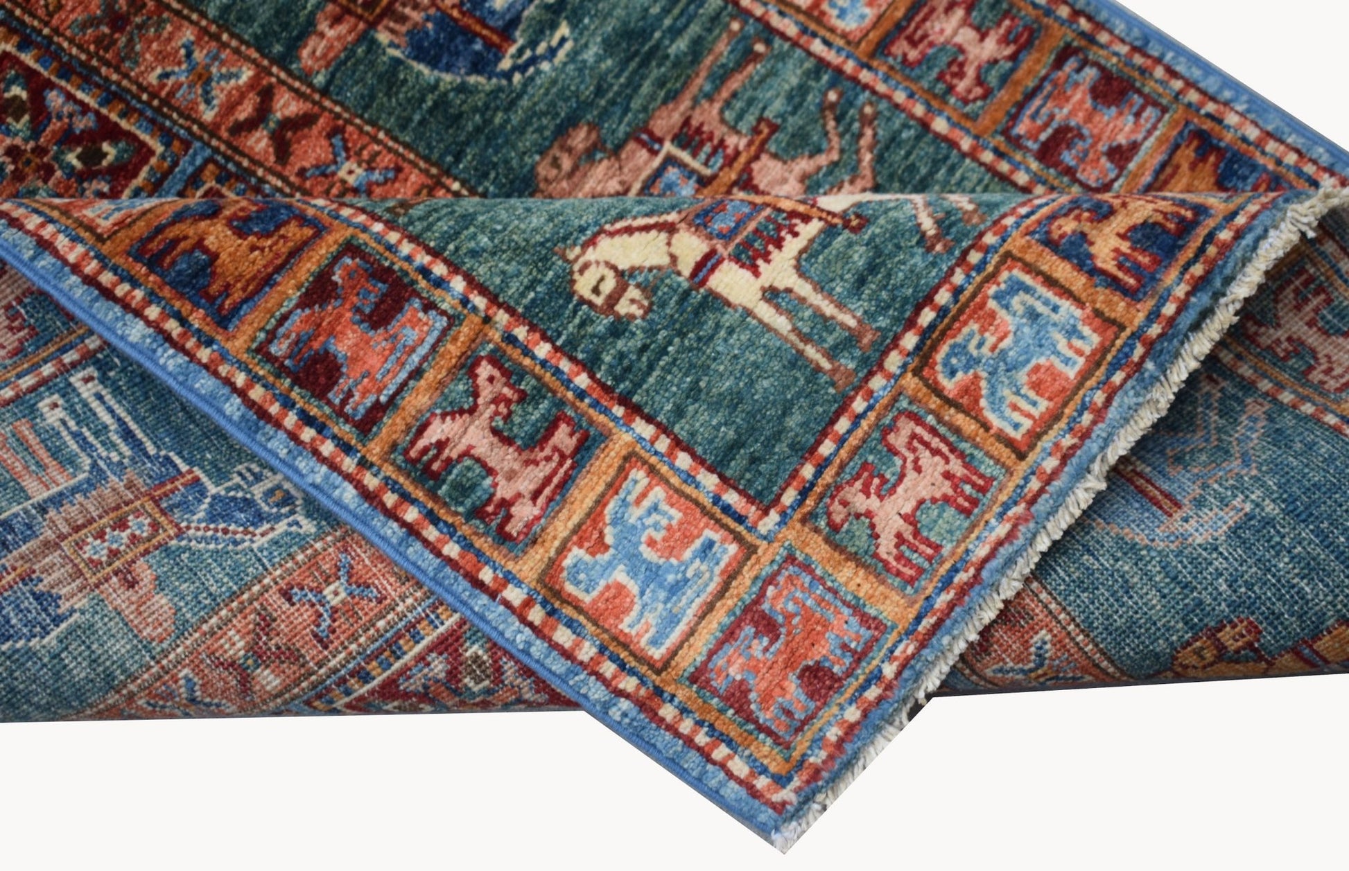 A folded Afghan Chobi rug featuring a teal field with animal motifs and a geometric border.