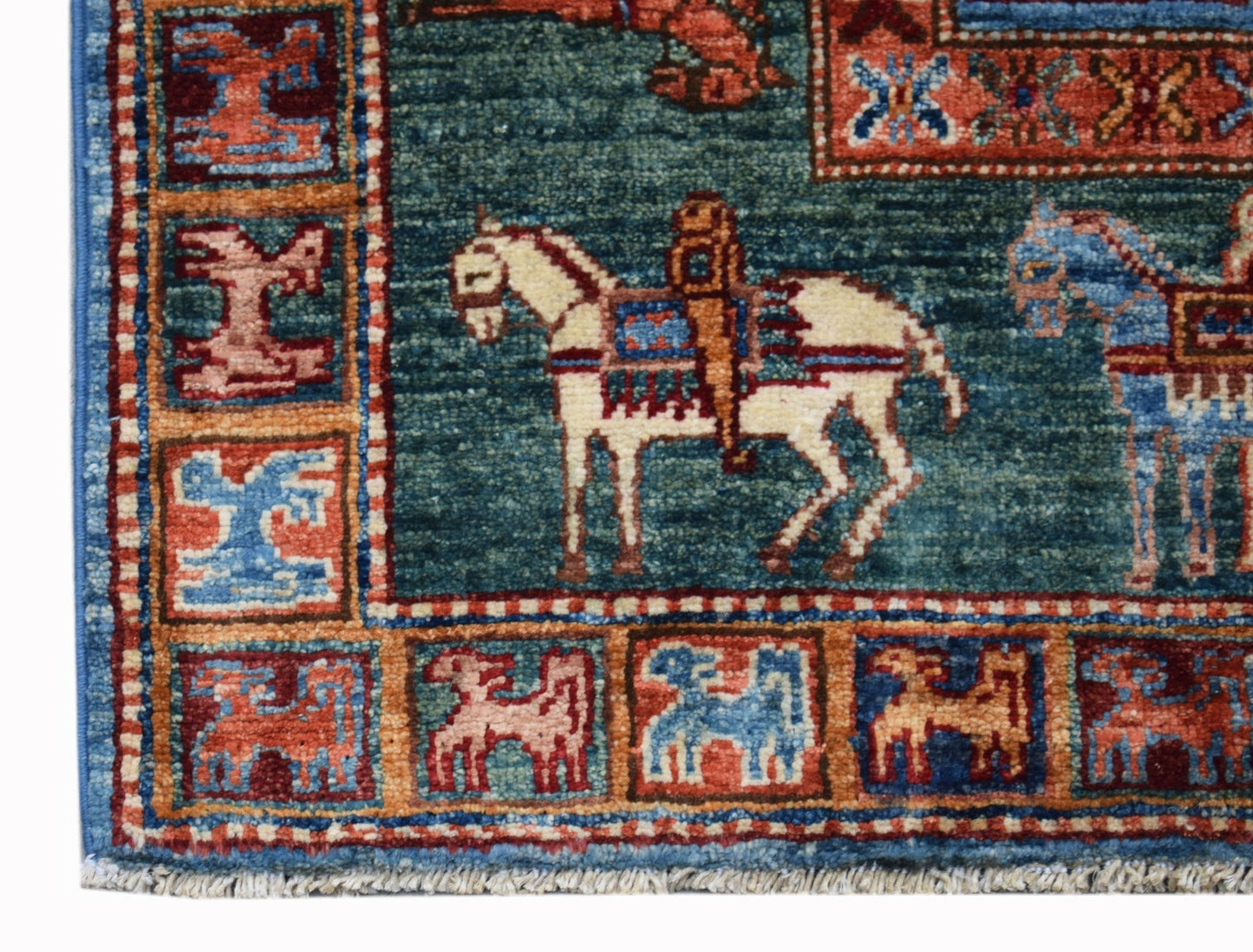 A handmade Afghan Chobi rug featuring a teal field with horse motifs and a patterned border.