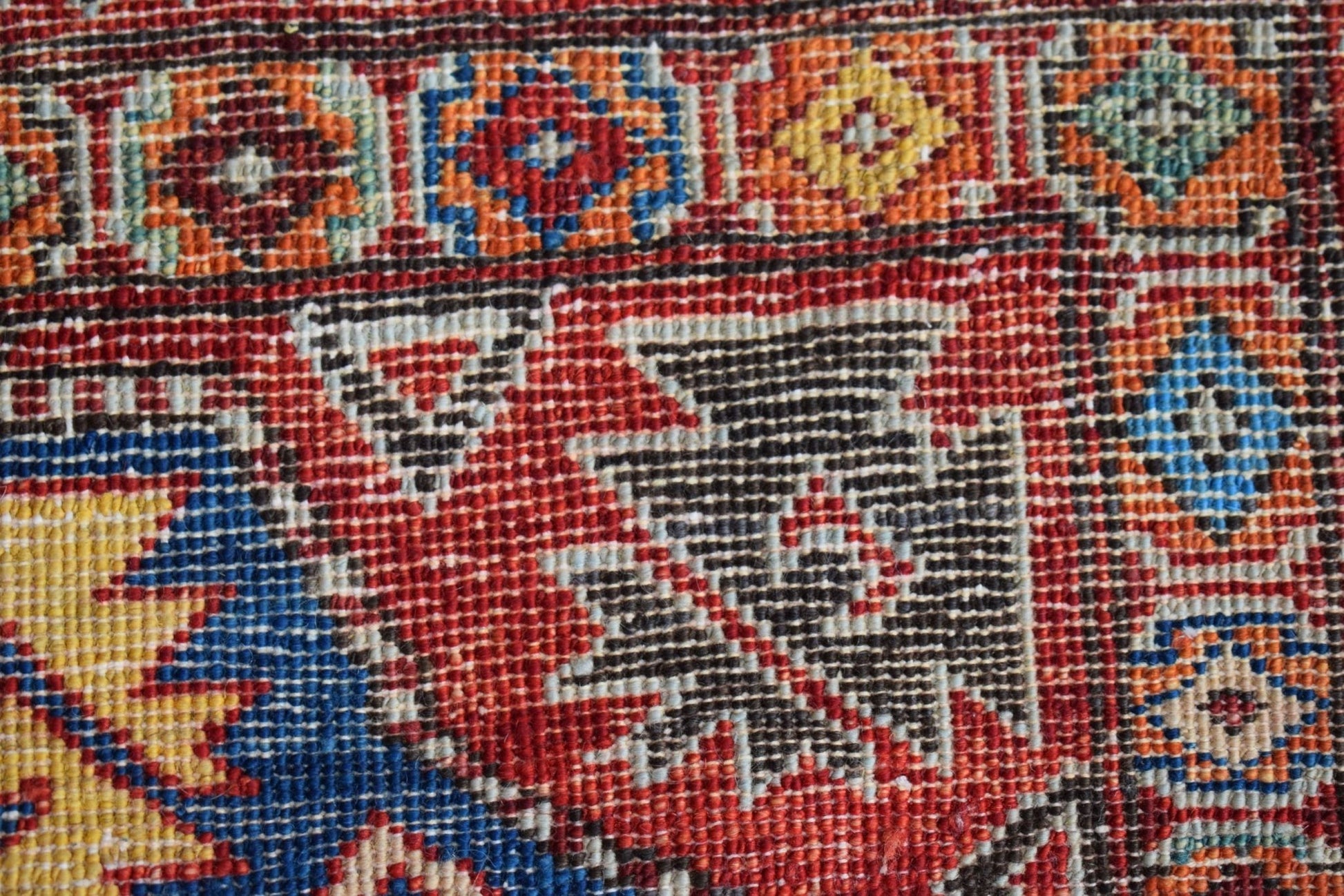 A close-up of a handmade Afghan Chobi rug featuring intricate geometric patterns in vibrant colors.