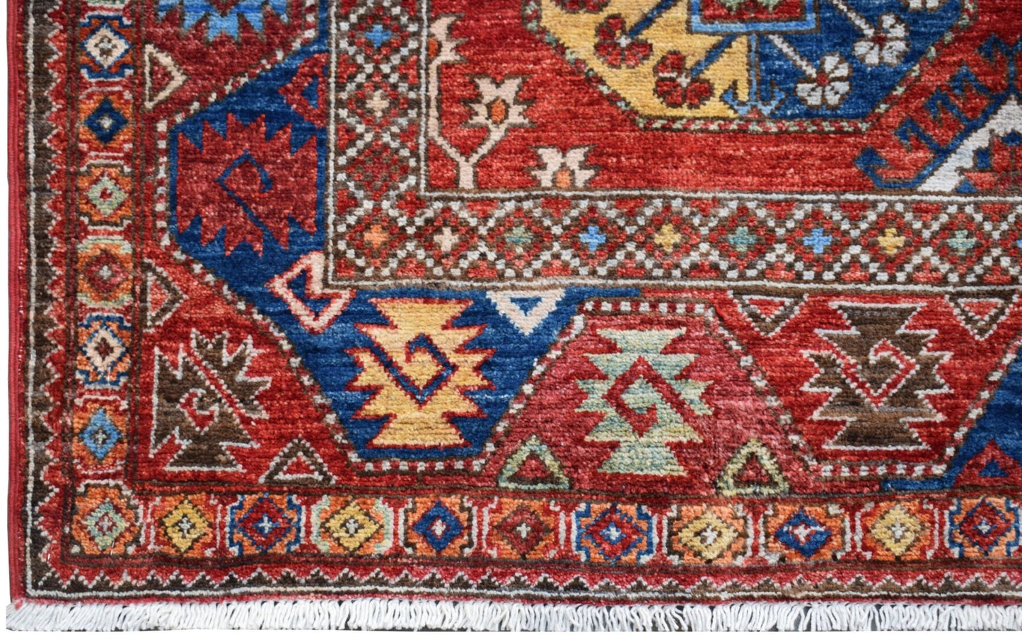 A handmade Afghan Chobi rug featuring a geometric pattern in red, blue, and yellow wool.