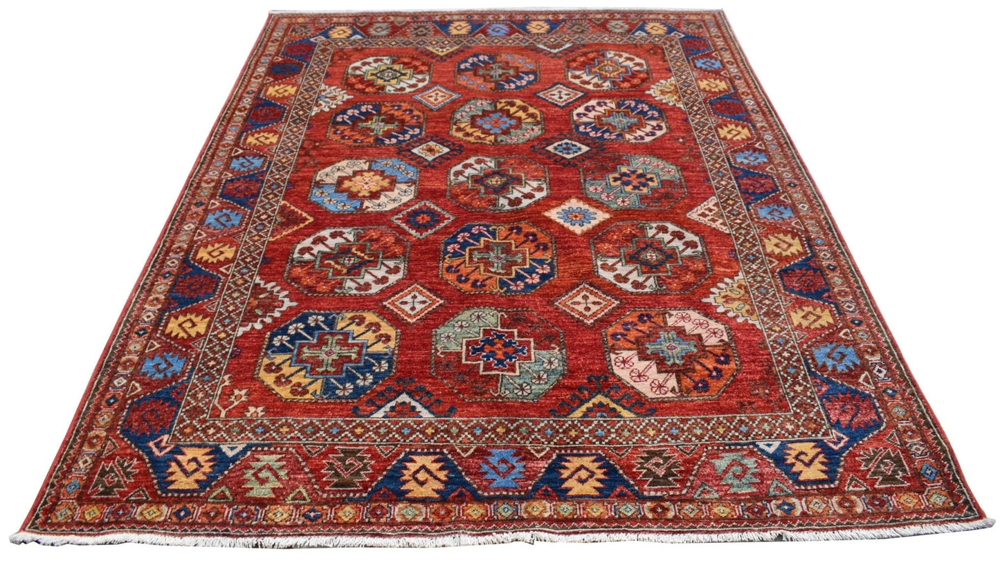 A handmade Afghan Chobi rug featuring a red field with repeating geometric octagonal motifs.
