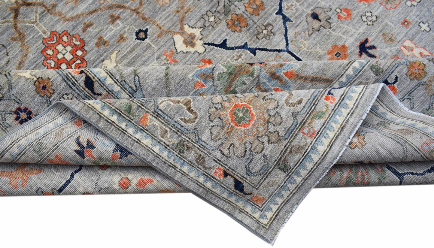 A handwoven Afghan Chobi rug featuring a traditional floral pattern in grey, orange, and blue.