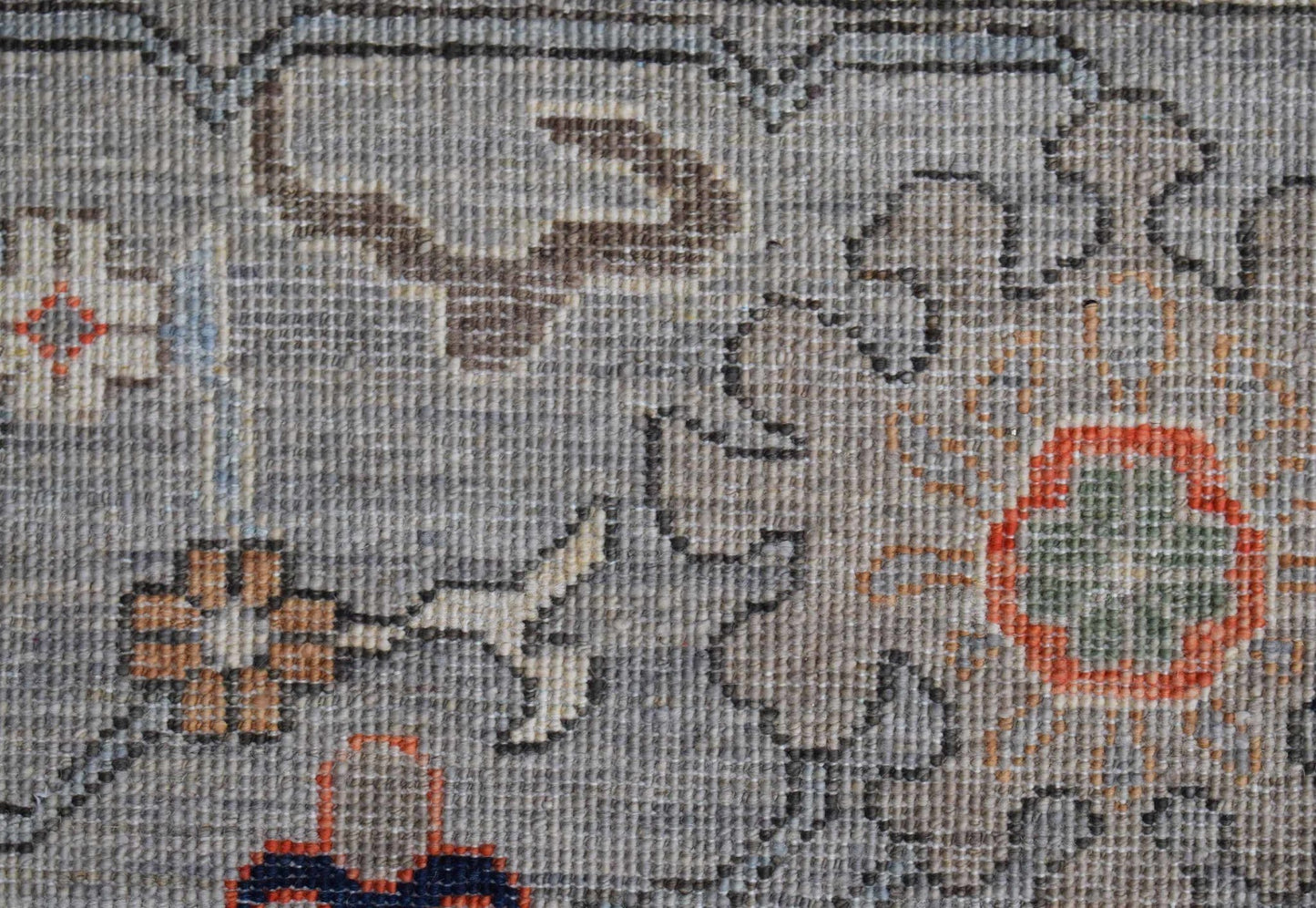 A close-up of a handwoven Afghan Chobi rug featuring intricate floral patterns in earthy tones.