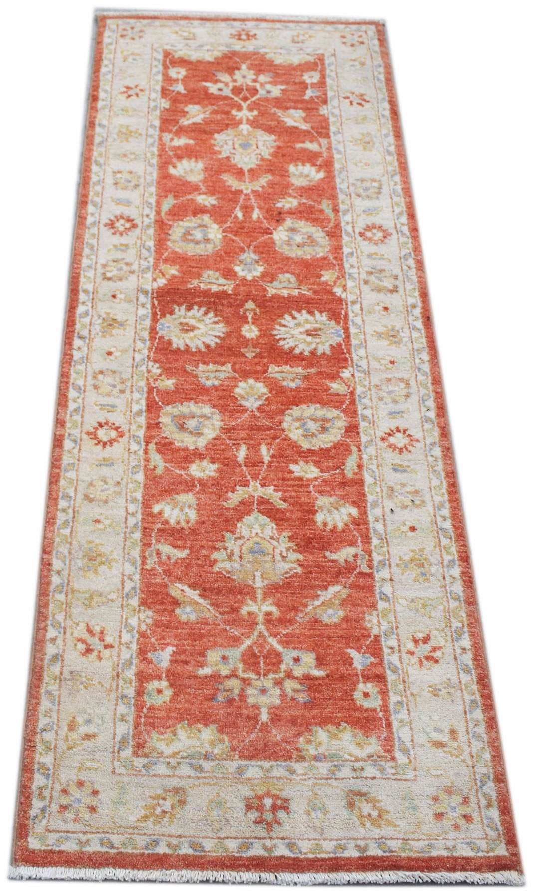 A handmade Afghan Chobi runner rug featuring a traditional floral pattern in terracotta and cream.