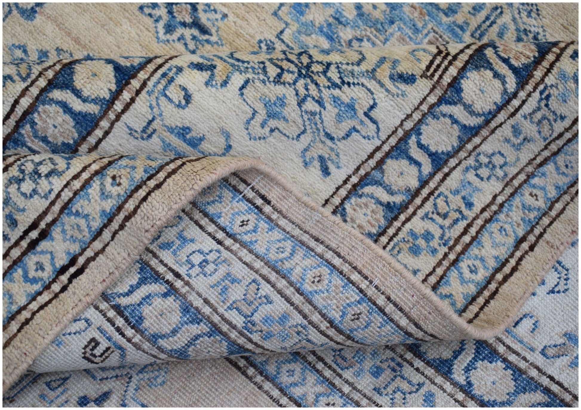 A handmade Afghan Super Kazakh rug featuring traditional blue and cream floral patterns.