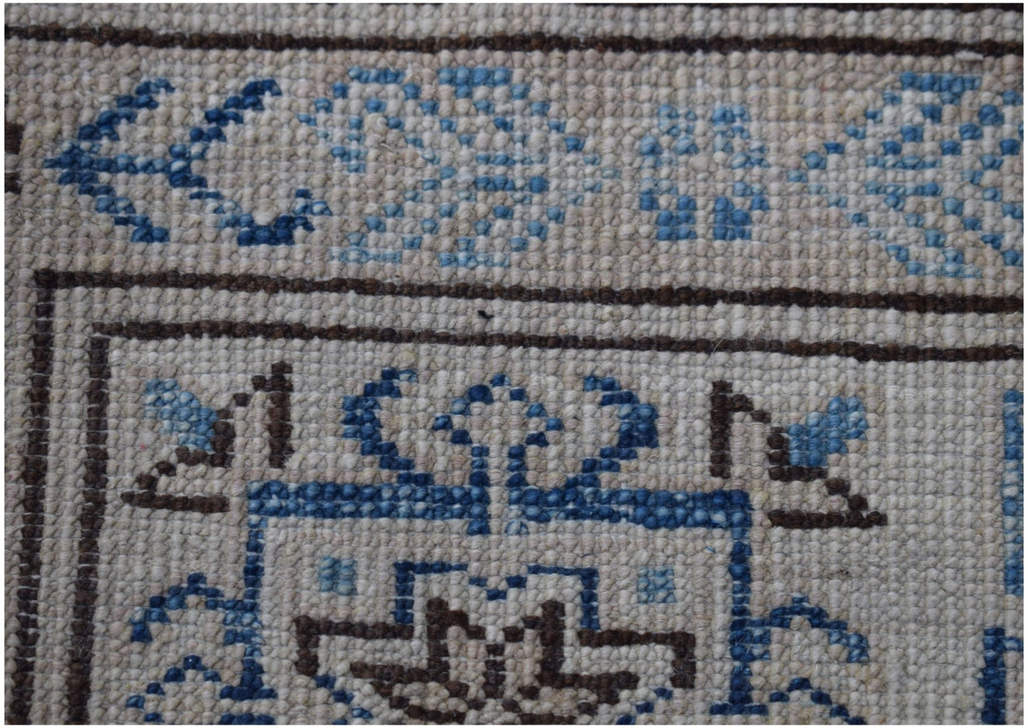 A close-up of an Afghan Super Kazakh rug featuring intricate blue and brown geometric patterns.
