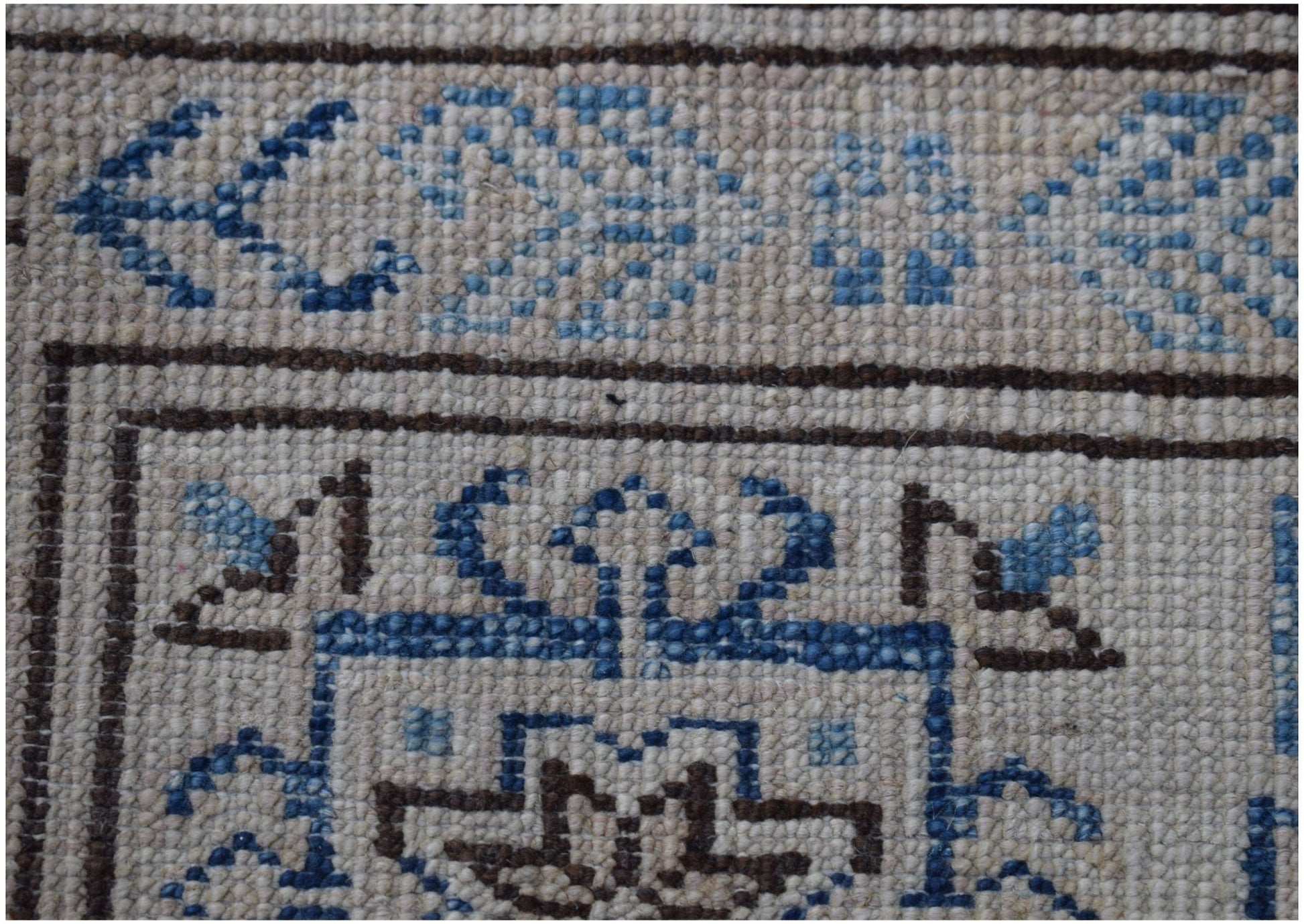 A close-up of an Afghan Super Kazakh rug featuring intricate blue and brown geometric patterns.