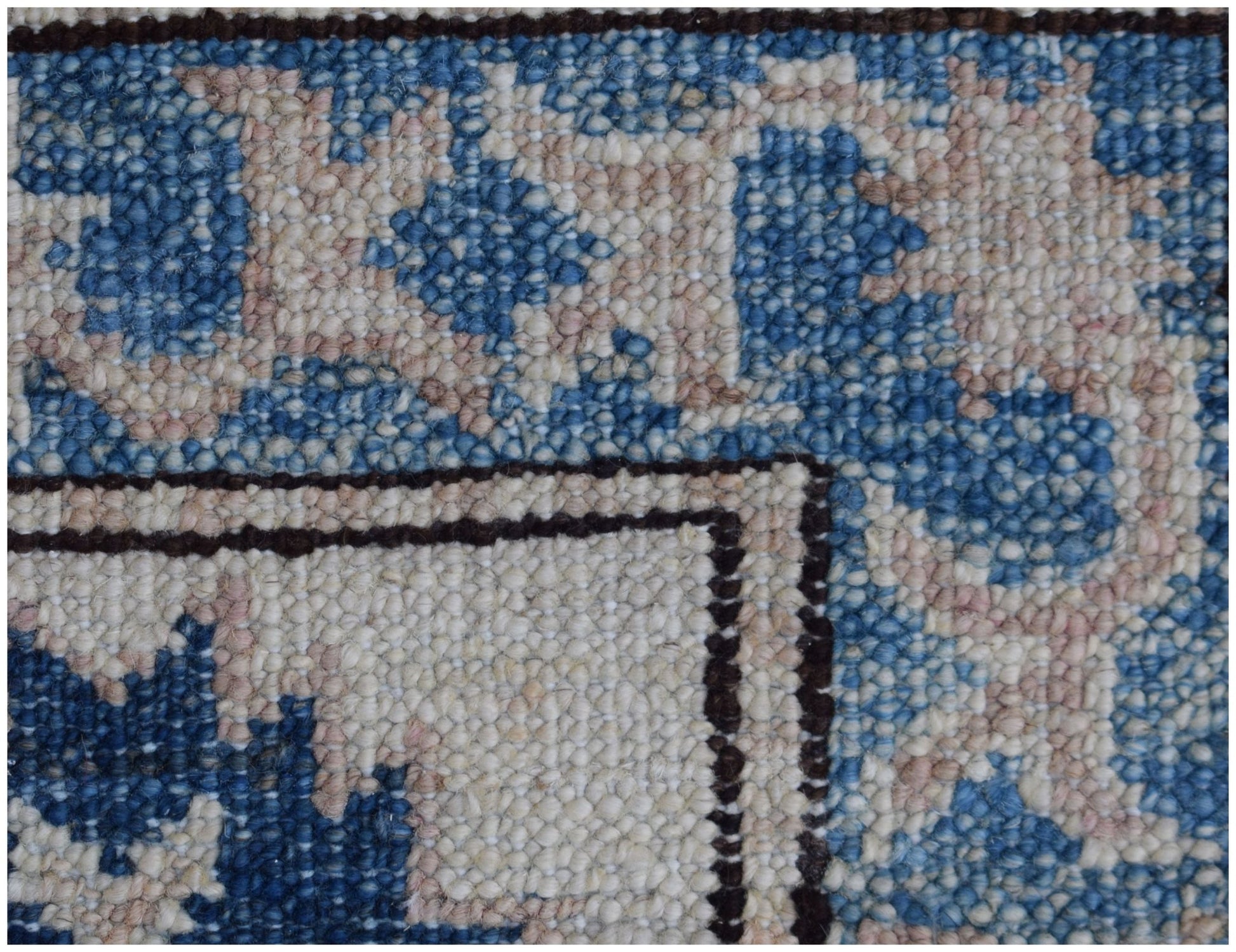 A close-up of a handmade Afghan Super Kazakh rug featuring traditional blue and cream wool patterns.