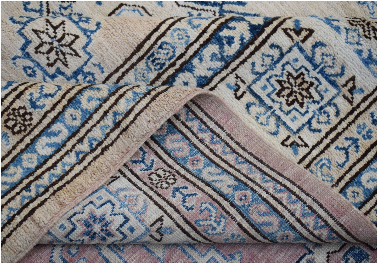 A handmade Afghan Super Kazakh rug featuring traditional geometric motifs in blue and cream tones.